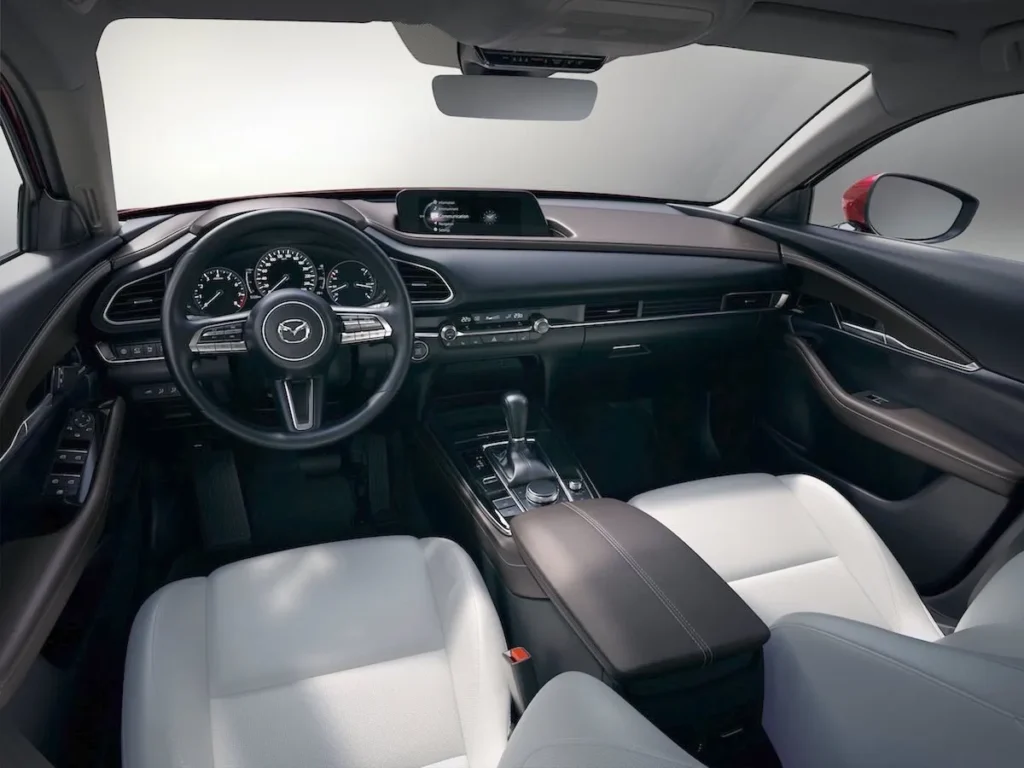 Interior del Mazda CX-30 rojo en oferta de renting, con salpicadero moderno, pantalla central y volante multifunción