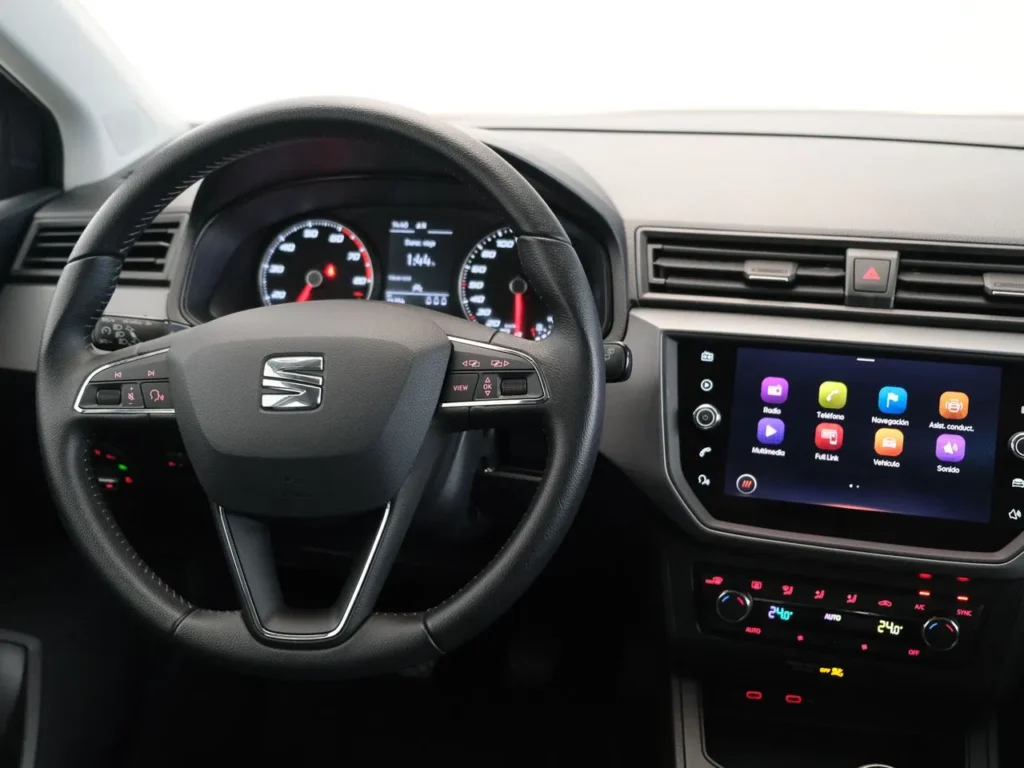 Interior del SEAT Ibiza blanco para renting, con salpicadero moderno, volante multifunción y pantalla central táctil encen…